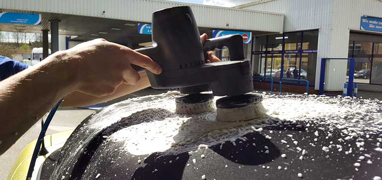 A technician polishing a vehicle’s exterior finish. / Un técnico pule el acabado exterior de un vehículo.