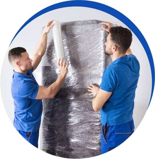 Dos profesionales de mudanza envuelven cuidadosamente un mueble / Two professional movers carefully wrap a piece of furniture