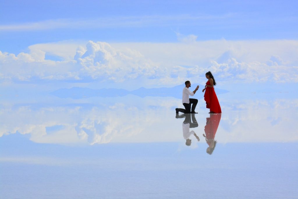 Visitantes fotografiados sobre el reflejo del Salar de Uyuni, imagen de Andes Salt Expeditions
