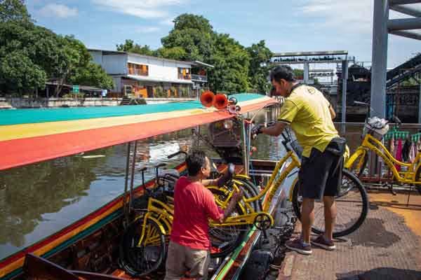 Guía ayuda a subir bicicletas a un barco durante el tour combinado