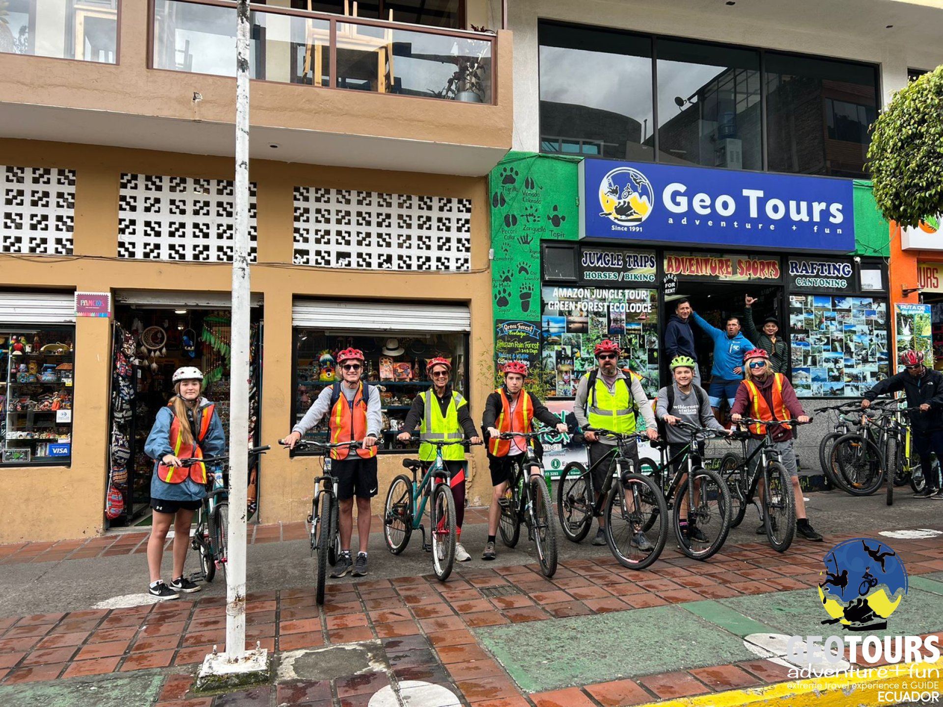 Ciclistas posan junto a la tienda de Geotours en Baños