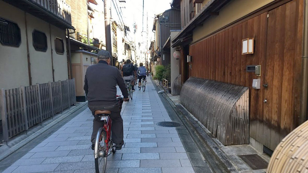 Cyclist on a narrow Kyoto lane / Ciclista en un callejón de Kioto