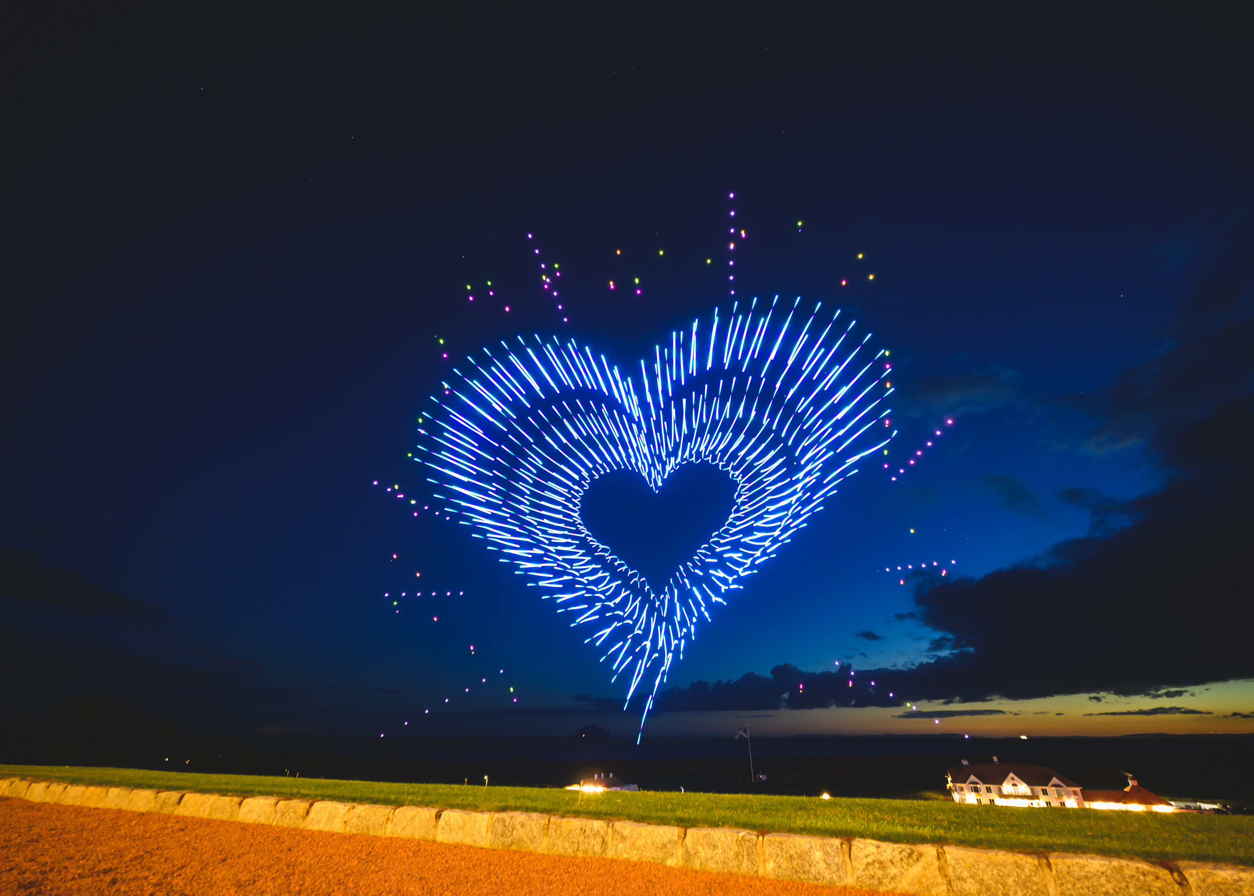 Illuminated drones forming an aerial display at dusk