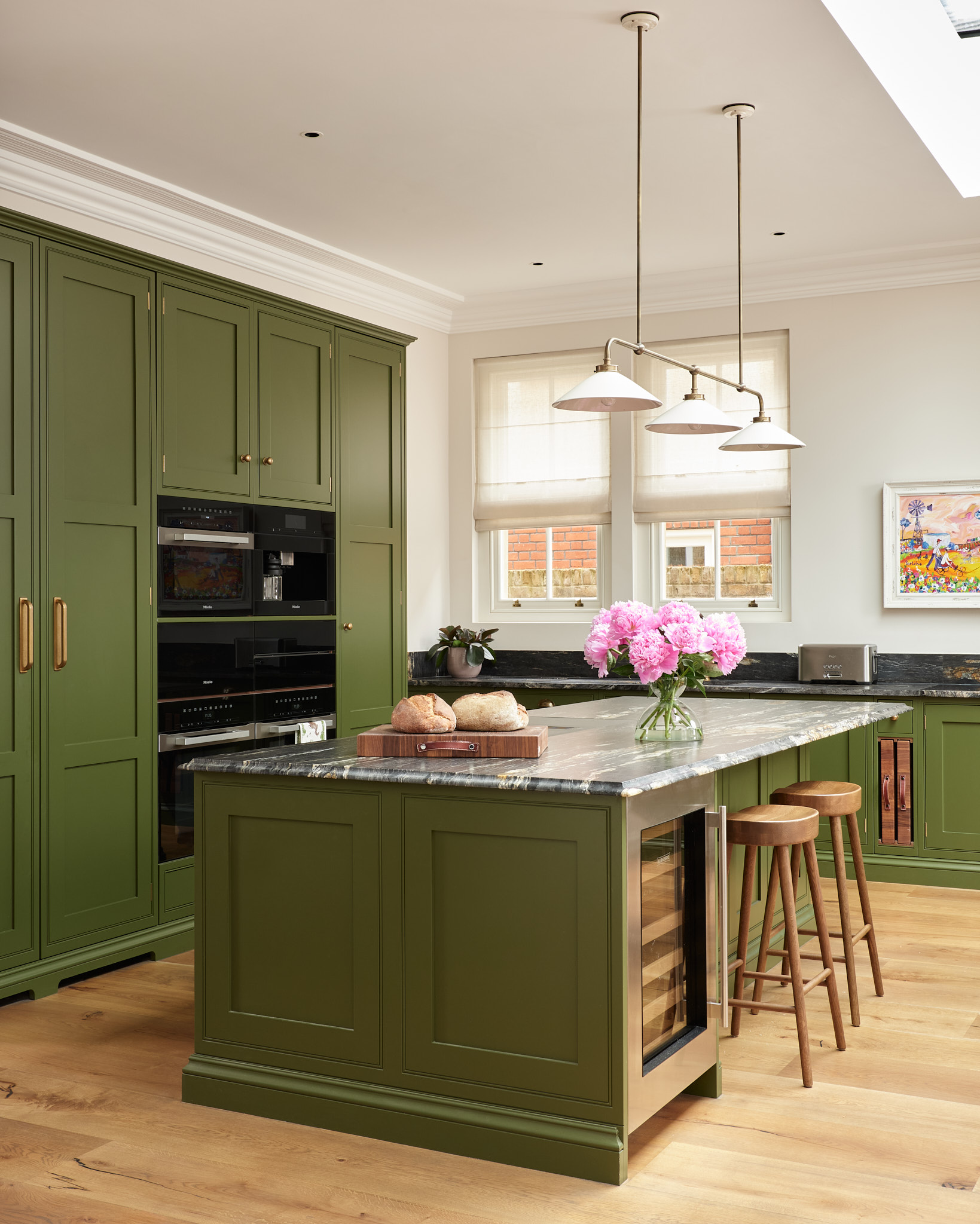 Green fitted kitchen with central island shown by John Lewis of Hungerford
