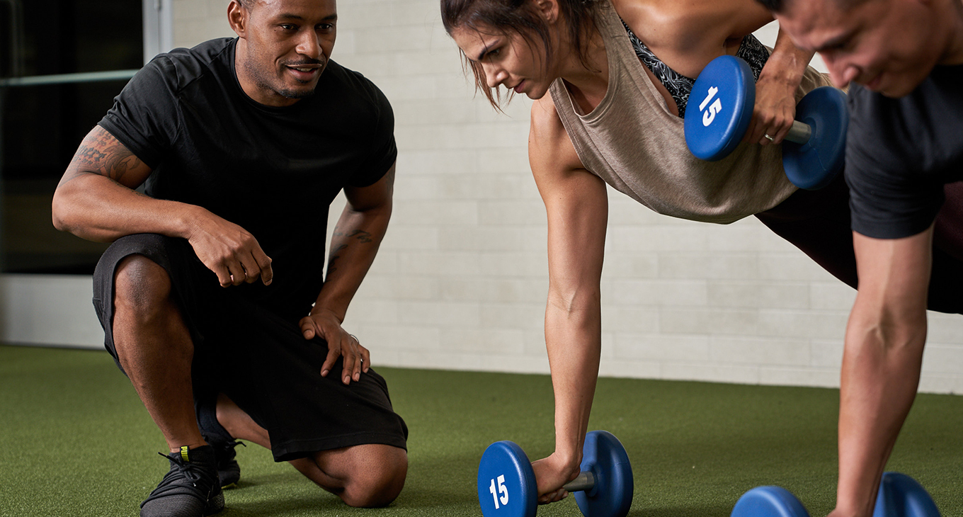 Personal trainer guiding a member using dumbbells at Onelife Fitness