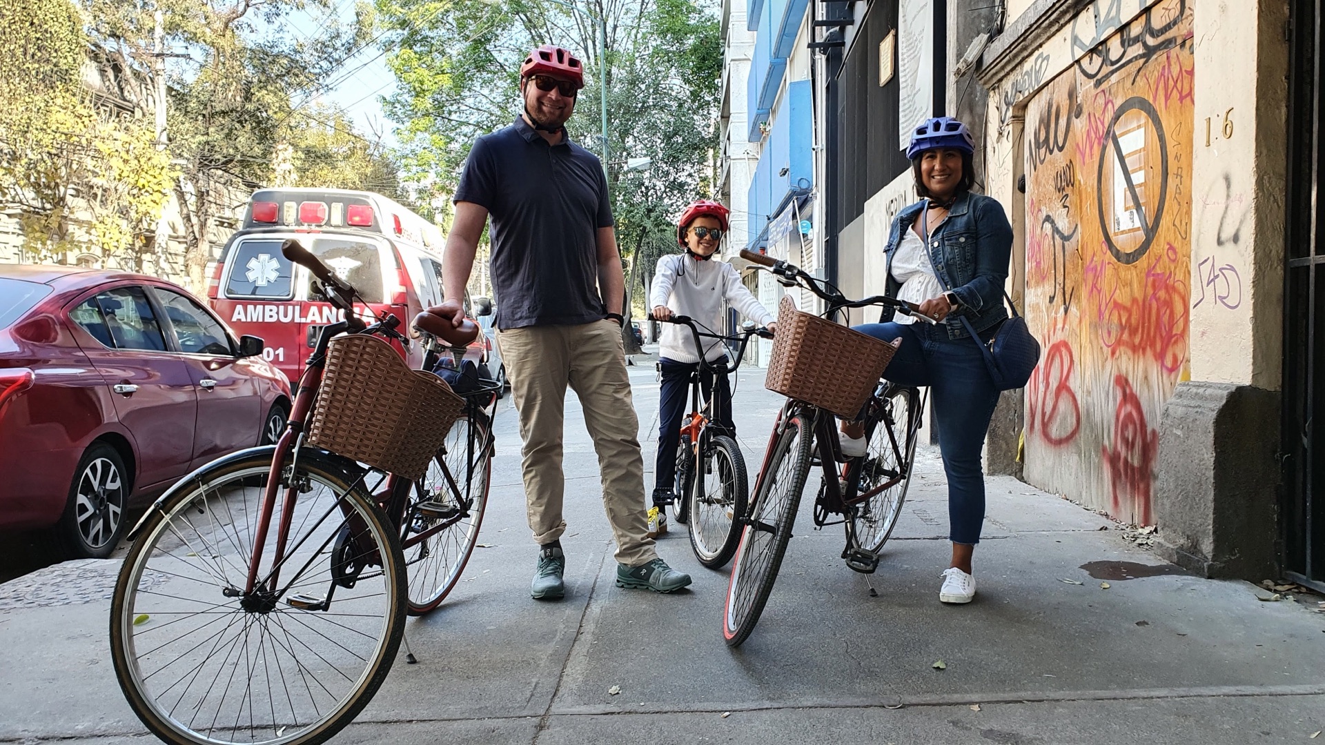 Participantes con bicicletas junto a un mural durante una ruta de arte urbano