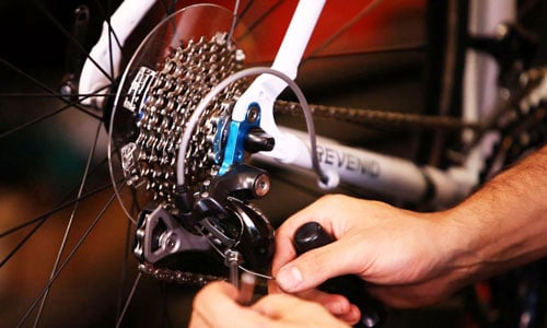 A bicycle rear derailleur being inspected and adjusted