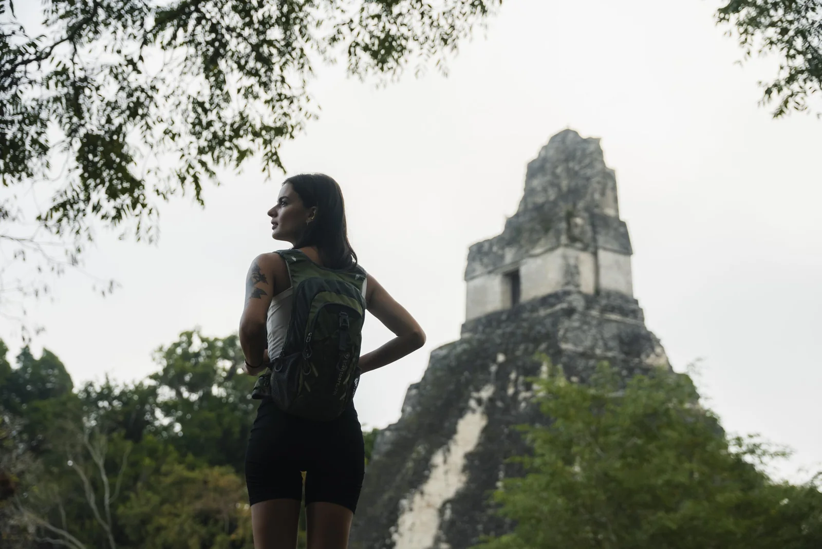 Visitante observa una estructura de Tikal entre la selva