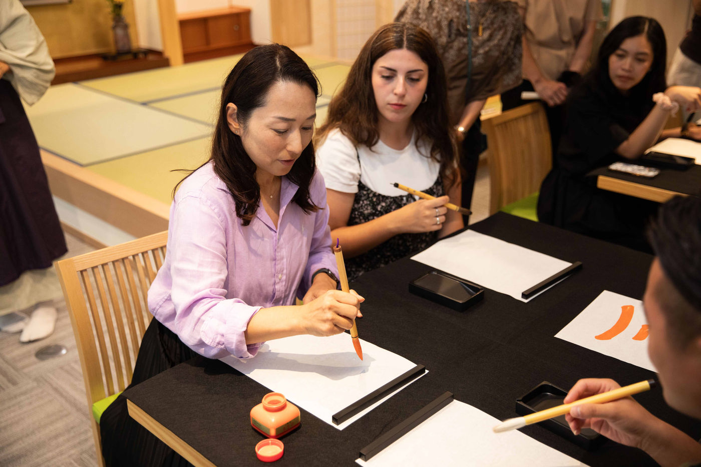 Participantes practican caligrafía japonesa en un taller de Asakusa