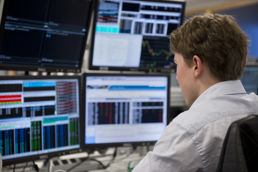 Trader working at a multi-screen desk shown on the SMB Training site