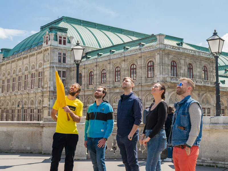 Guía con camiseta amarilla explica un edificio a los visitantes